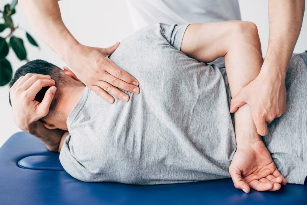 A man in a grey shirt getting an adjustment from a chiropractor in El Paso.