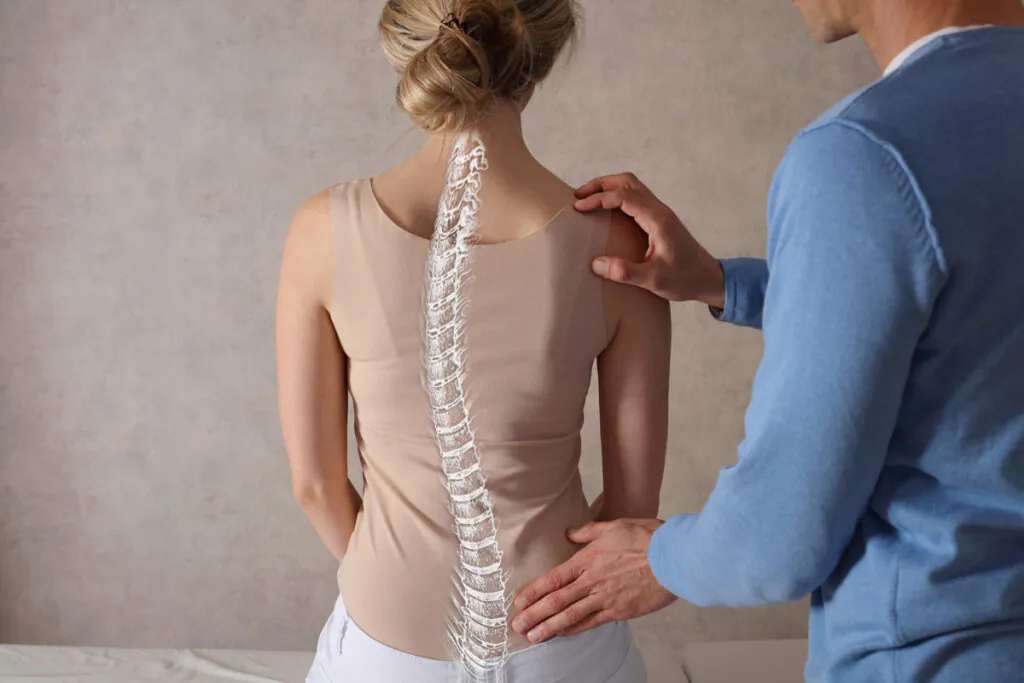 A doctor adjusting a woman sitting upright with scoliosis in El Paso.