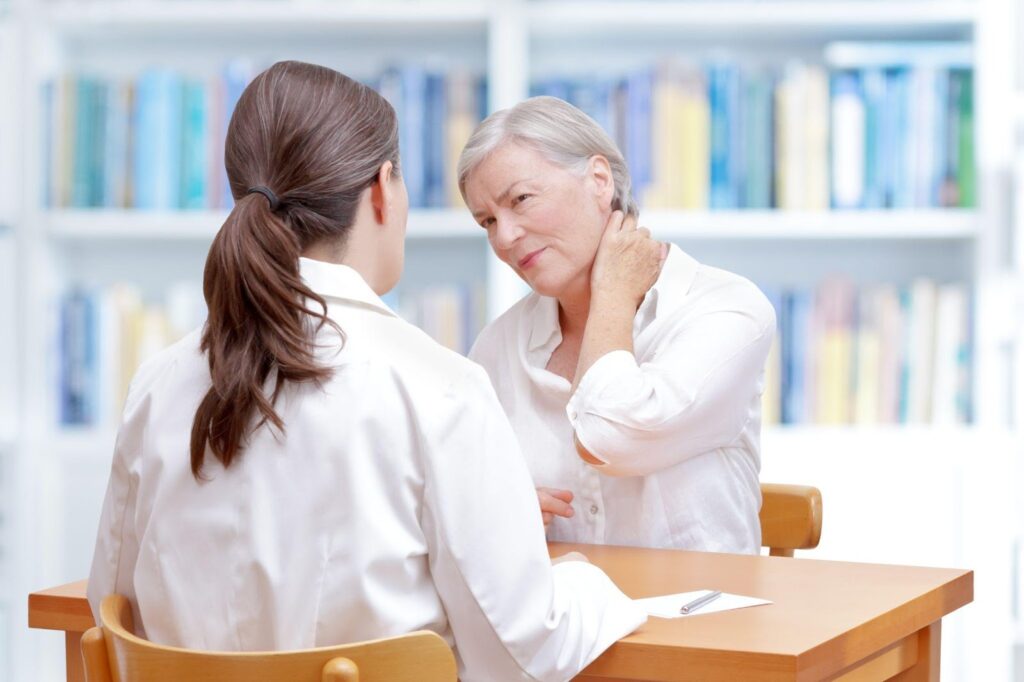 An older woman with fibromyalgia pain speaking with a physical therapist